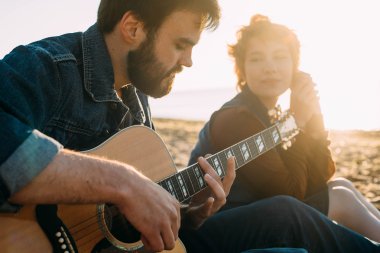 Çift sahilde gitar çalmak