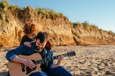 Çift sahilde gitar çalmak