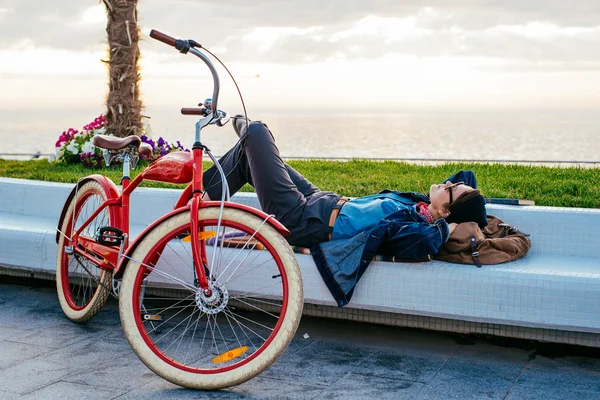 Mujer con bicicleta descansando en la orilla del mar — Foto de Stock