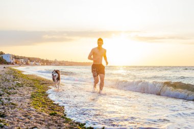 Köpek ile kumsalda koşan adam