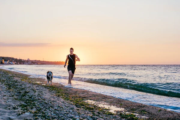 Hombre corriendo con perro en la playa —  Fotos de Stock