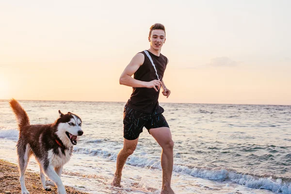 Чоловік біжить з собакою на пляжі — стокове фото
