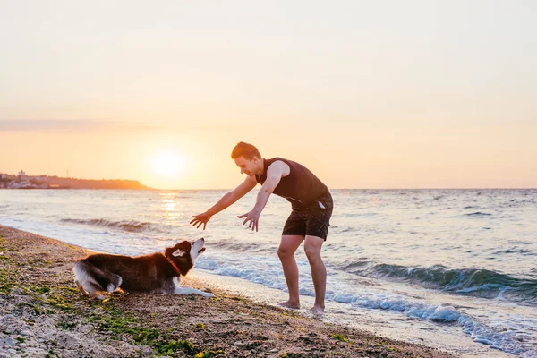 Jeune homme avec chien sur la plage — Photo