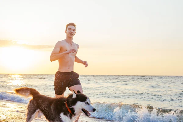 Homem correndo com cão na praia — Fotografia de Stock