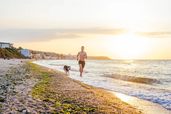 Hombre corriendo con perro en la playa —  Fotos de Stock