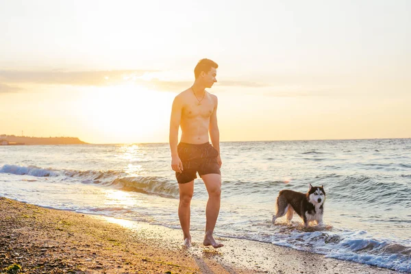 Jeune homme avec chien sur la plage — Photo