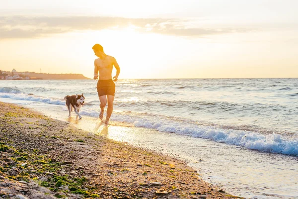 Człowiek działa z psem na plażę — Zdjęcie stockowe