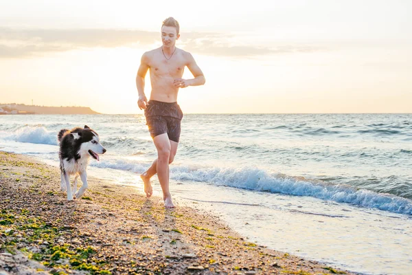 人与狗跑在海滩上 — 图库照片