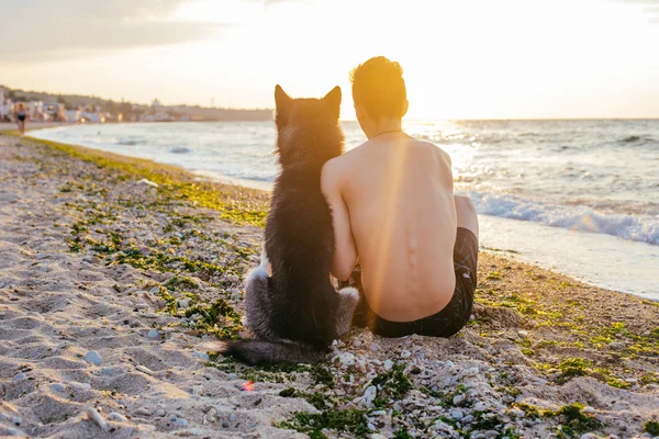 Jeune homme avec chien sur la plage — Photo