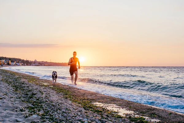 Hombre corriendo con perro en la playa —  Fotos de Stock
