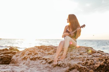 Sahilde kadın oynarken ukulele