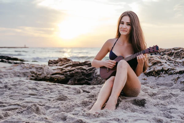 Женщина играет на укулеле на пляже — стоковое фото