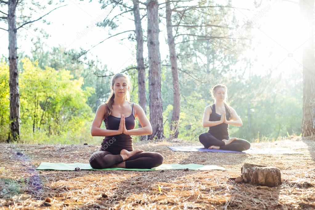 two women practicing yoga in the wood