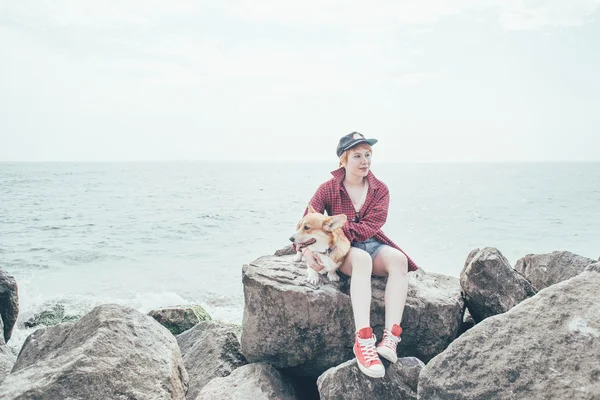 Рыжая девушка с валлийским корги-догом на берегу моря — стоковое фото