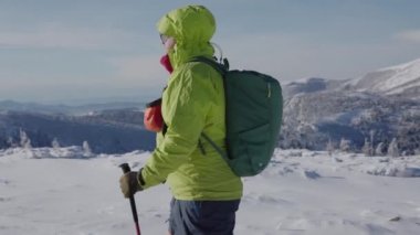 Karlı kış dağlarında iki Sibirya köpeğiyle yürüyüş yapan adamın 4k fotoğrafı.