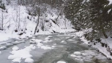 Güzel nehrin havadan çekilmiş 4K görüntüsü. Karanlık ve karlı bir havada dondurucu nehrin üzerinde hareket eden bir dron. Soğuk kış konsepti