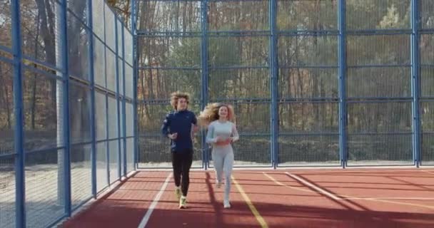 一对年轻的运动型夫妇在秋天公园的操场上奔跑 健康和积极的观念 — 图库视频影像
