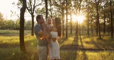 Aile oyunu ve eğlence. Baba, anne ve kız güzel yeşil parkta yaz günbatımının tadını çıkarıyorlar.