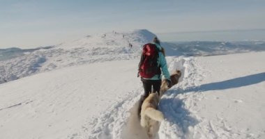 Mavi ceketli bir kadın karlı dağlarda doğa yürüyüşü yapıyor. Yürüyüşçü, güzel kış arka planına karşı. Etkin yaşam tarzı ve uzak yerlere seyahat kavramı