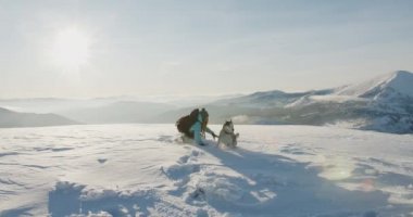 Mavi ceketli bir kadın karlı dağlarda doğa yürüyüşü yapıyor. Yürüyüşçü, güzel kış arka planına karşı. Etkin yaşam tarzı ve uzak yerlere seyahat kavramı