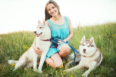 young caucasian female with two siberian husky dog sitting on the field in crimea mountains