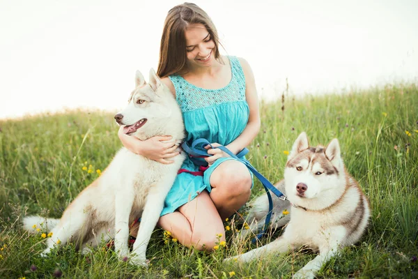 Jovem caucasiana fêmea com dois siberianos husky cão sentado no campo em crimea montanhas — Fotografia de Stock