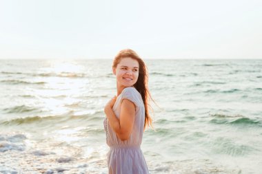 genç güzel beyaz kadın gündoğumu veya günbatımı sırasında plajda güneşin tadını