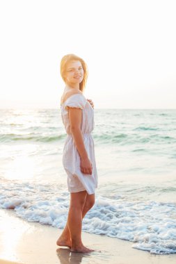 genç güzel beyaz kadın gündoğumu veya günbatımı sırasında plajda güneşin tadını