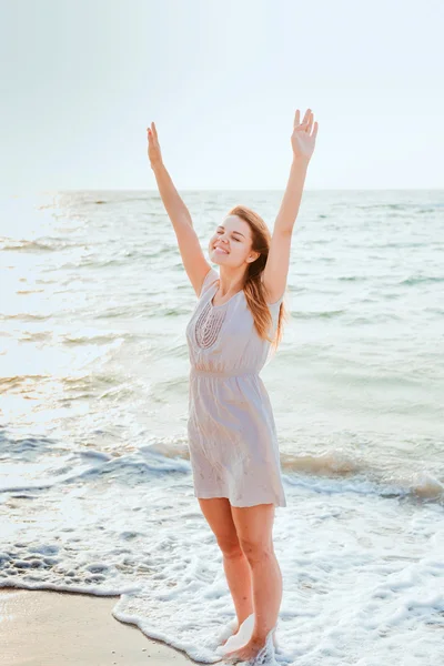 Jovem bela mulher caucasiana desfrutando do sol na praia durante o nascer do sol ou pôr do sol — Fotografia de Stock