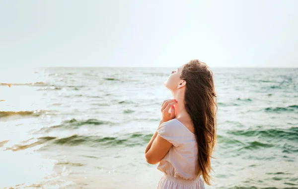 Joven hermosa hembra caucásica disfrutando del sol en la playa al amanecer o al atardecer — Foto de Stock