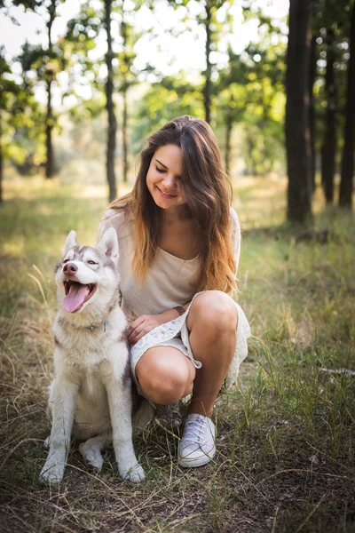 Joven caucásico hembra con siberiano husky cachorro en parque — Foto de Stock