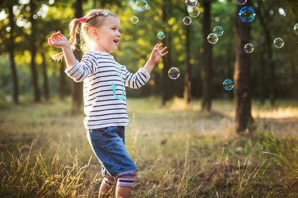 Маленька дівчинка грає з бульбашковим вентилятором в парку — стокове фото