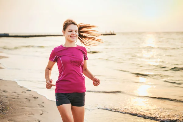 Systemem kobieta. Kobiece kobieta lekkoatletka joggingu podczas słońca na plaży. — Zdjęcie stockowe