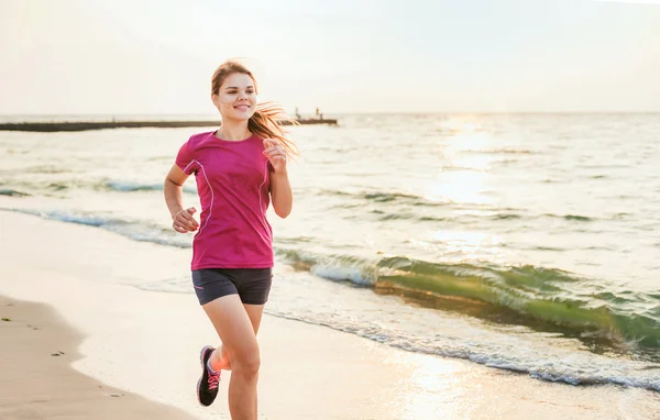 Systemem kobieta. Kobiece kobieta lekkoatletka joggingu podczas słońca na plaży. — Zdjęcie stockowe