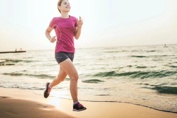 Systemem kobieta. Kobiece kobieta lekkoatletka joggingu podczas słońca na plaży. — Zdjęcie stockowe