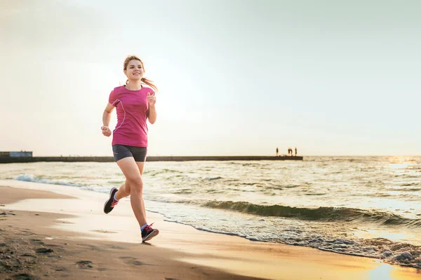 Systemem kobieta. Kobiece kobieta lekkoatletka joggingu podczas słońca na plaży. — Zdjęcie stockowe