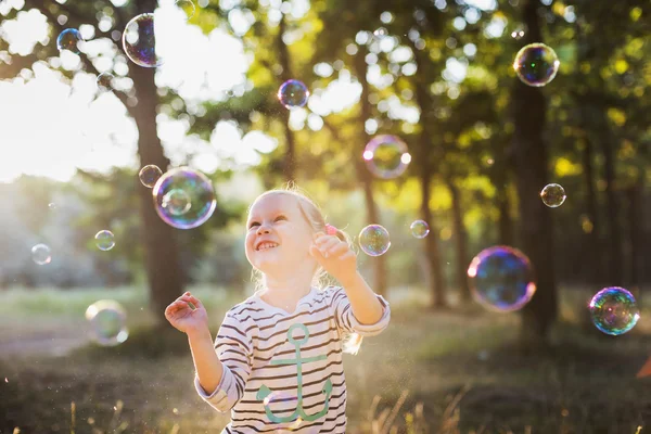 Маленька дівчинка грає з бульбашковим вентилятором в парку — стокове фото