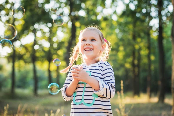 Liten flicka spelar med bubbla fläkt i parken — Stockfoto
