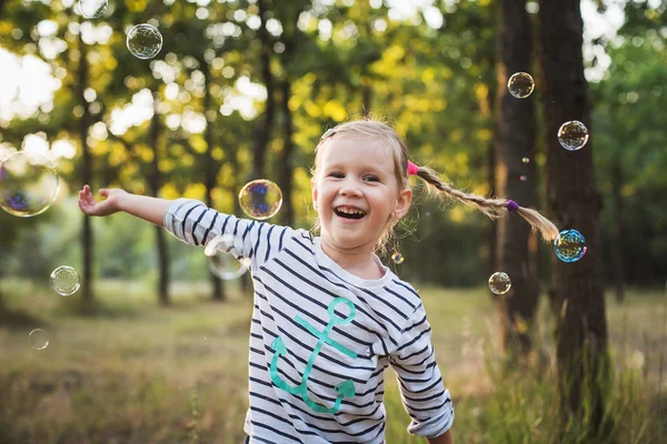 Liten flicka spelar med bubbla fläkt i parken — Stockfoto