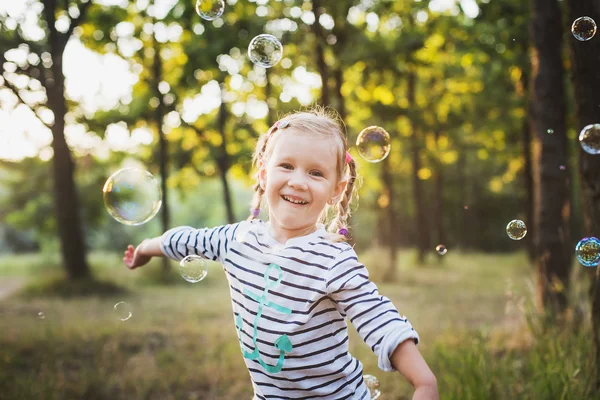 Liten flicka spelar med bubbla fläkt i parken — Stockfoto