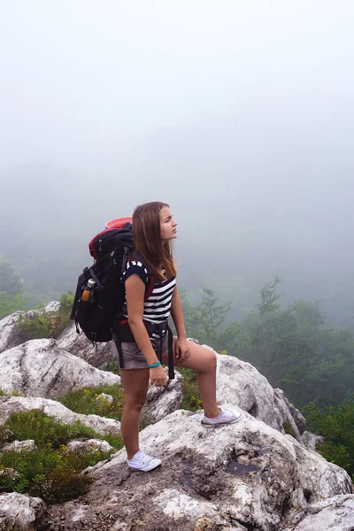 young caucasian female hiker in mountains, woman hiking in the fog with a backpack in Crimea