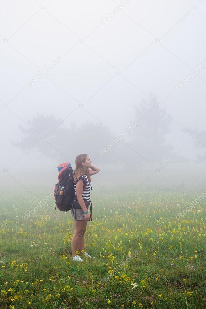 young caucasian female hiker in mountains, woman hiking in the fog with a backpack in Crimea