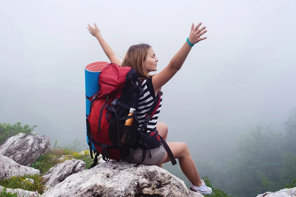 Joven mujer caucásica excursionista en las montañas, mujer senderismo en la niebla con una mochila —  Fotos de Stock