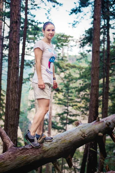 Caucasian hiker woman on trek in mountains living a healthy active lifestyle. Hiker girl on nature landscape hike in Crimea balancing on a tree, happy free female in the wood. — Stock Photo, Image