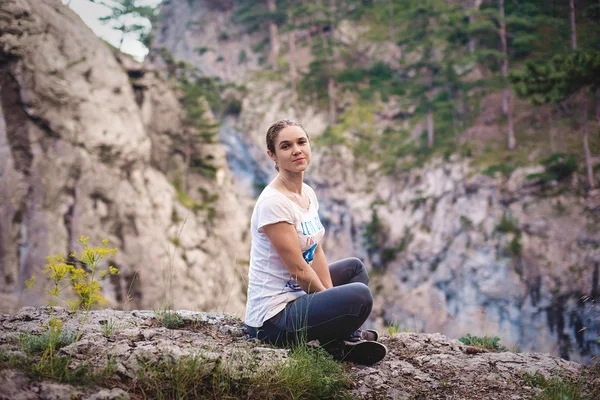 Young caucasian female sitting on a cliff in Crimea mountains — Stock Photo, Image