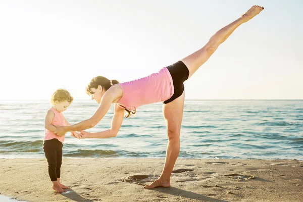 Allenamento in famiglia - madre e figlia che fanno esercizi sulla spiaggia . — Foto Stock