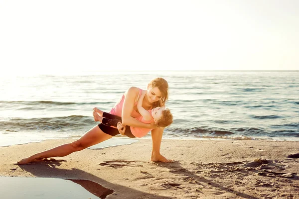 Familientraining - Mutter und Tochter machen Übungen am Strand. — Stockfoto