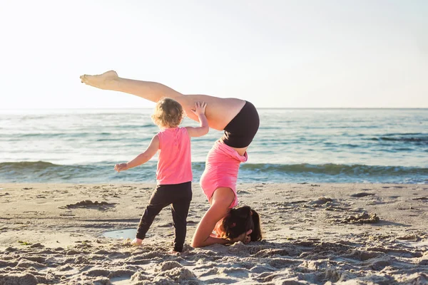 Entrenamiento familiar - madre e hija haciendo ejercicios en la playa. — Foto de Stock