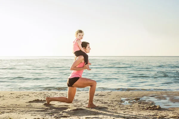 Treino familiar - mãe e filha fazendo exercícios na praia . — Fotografia de Stock