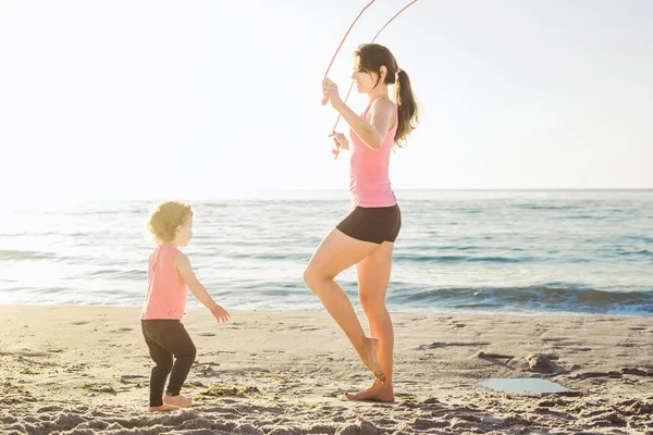 Familientraining - Mutter und Tochter machen Übungen am Strand. — Stockfoto